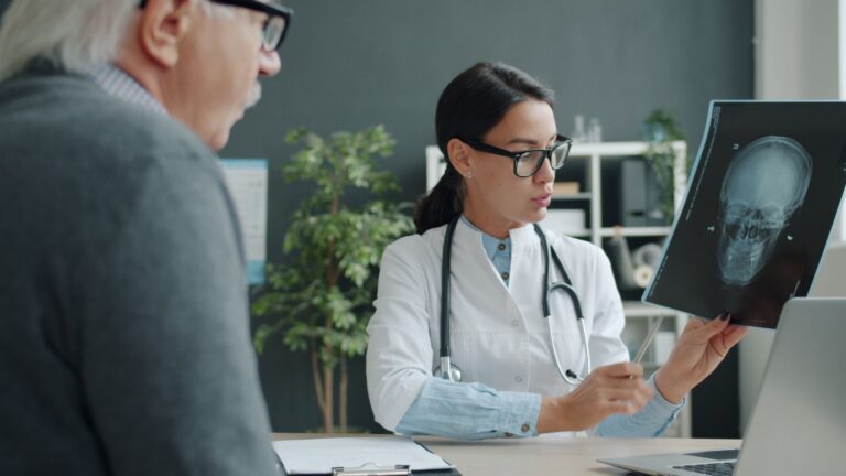 Pacient care discută cu medicul într-un cabinet luminos, cu un carnet de notițe pe masă