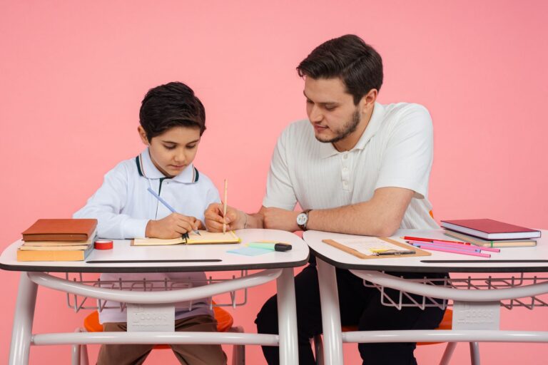 Birou de student cu mai multe manuale deschise, caiete și un pahar cu creioane colorate