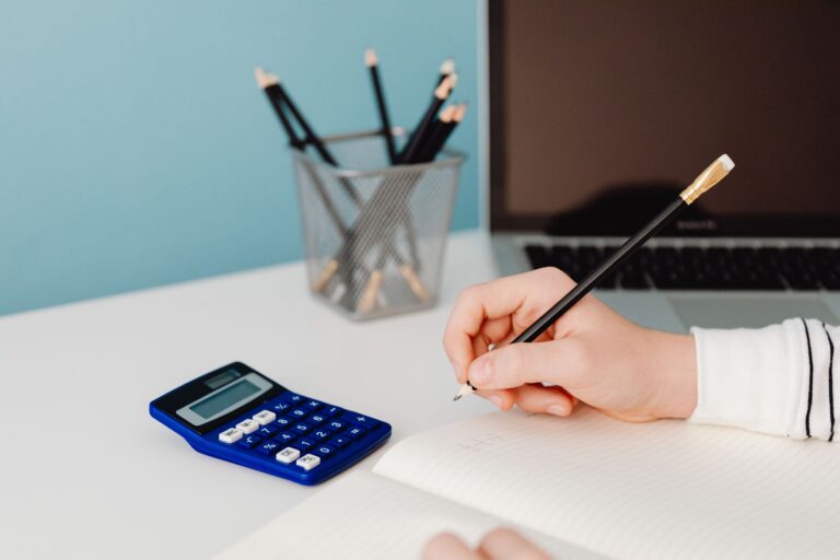 Calculator, caiet cu cifre și pix pe biroul unui antreprenor care își analizează costurile